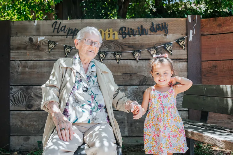 The guest of honor at a 90th birthday holding hands with a little girl