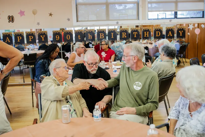 Guests greeting the guest of honor under a birthday banner