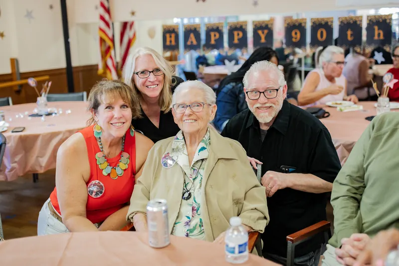 Guests gathered around the guest of honor at a 90th birthday party