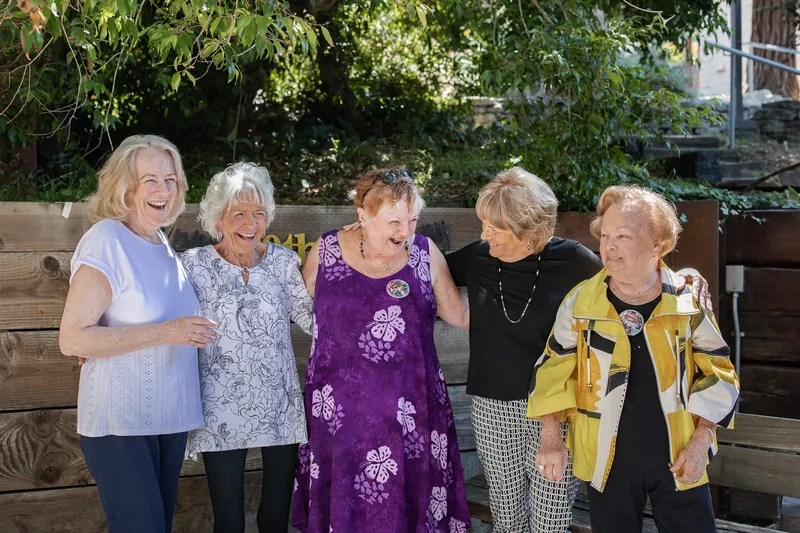 Five friends laughing together at a 90th birthday party
