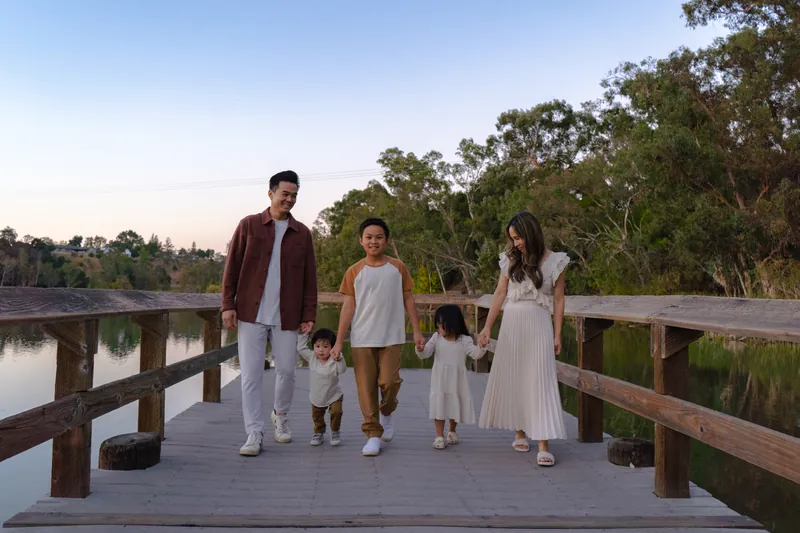 A family of five walking hand in hand on a lakeside dock