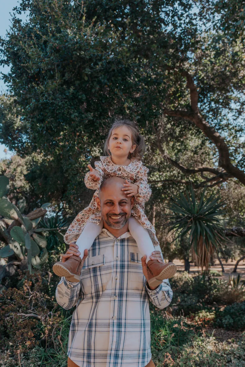A girl riding on her dad's shoulders