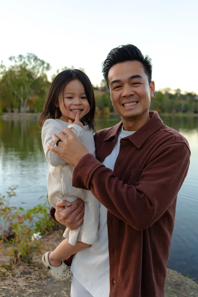 A dad holding his grinning daughter