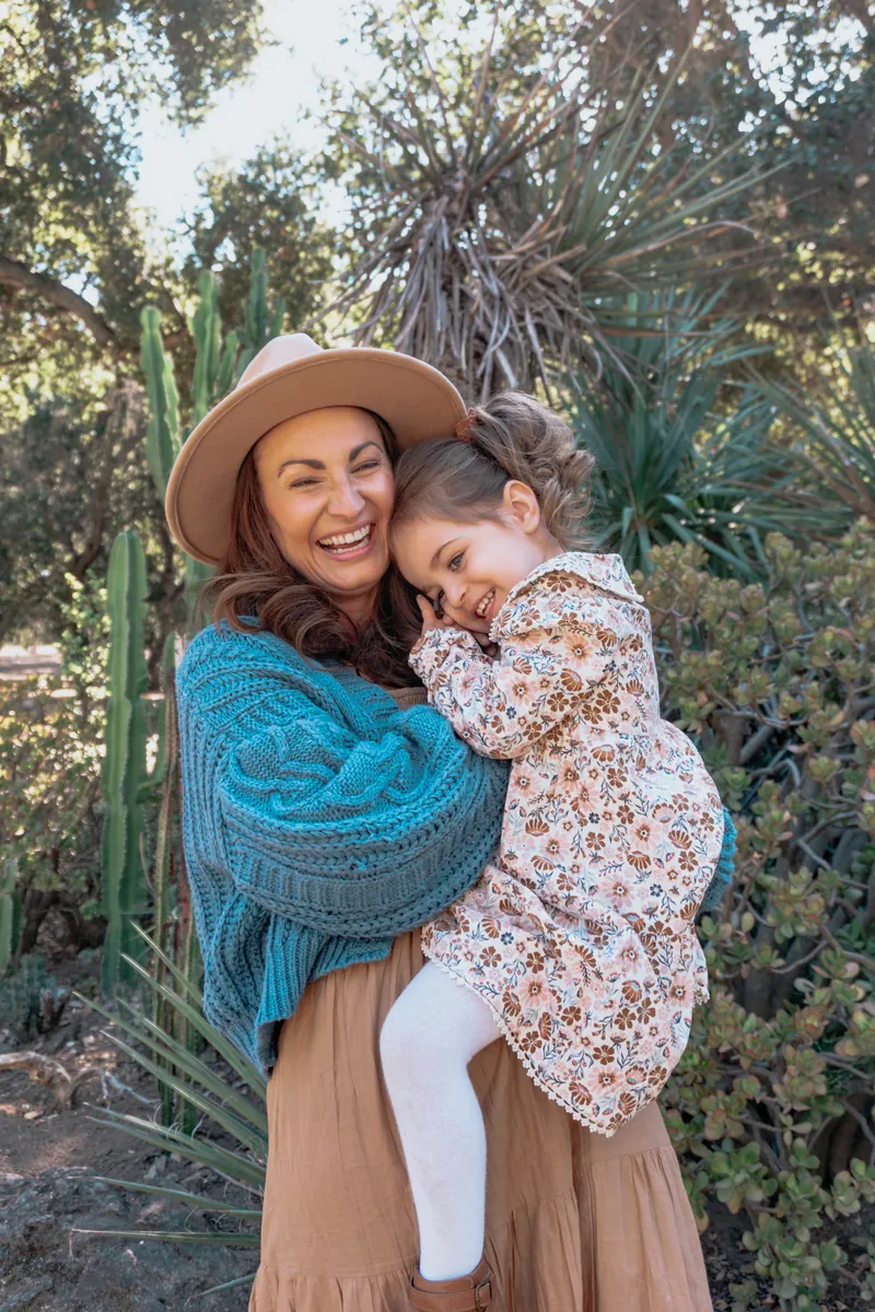 A mom hugging her daughter, both laughing