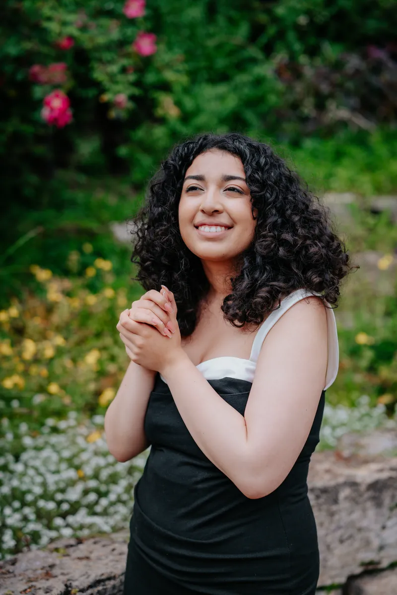 A senior laughing with her hands clasped in a garden