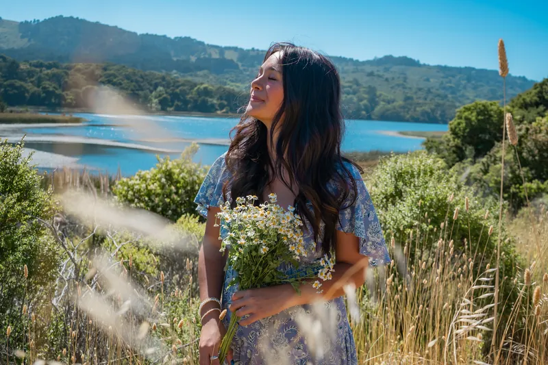 Holding daisies above a lagoon