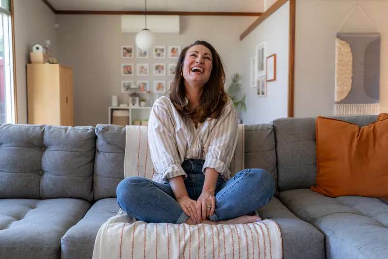 Laughing cross-legged on a couch