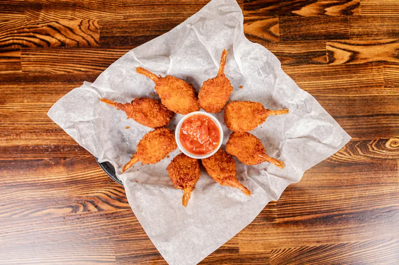Fried shrimp arranged in a circle around a cup of red sauce