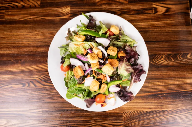 A green salad with croutons, tomatoes, red onion, and olives, from above