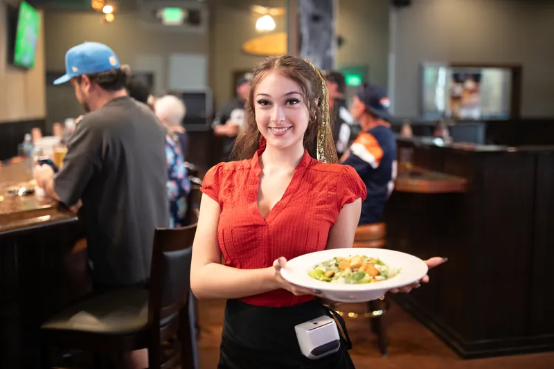 A server carries a salad through the bar