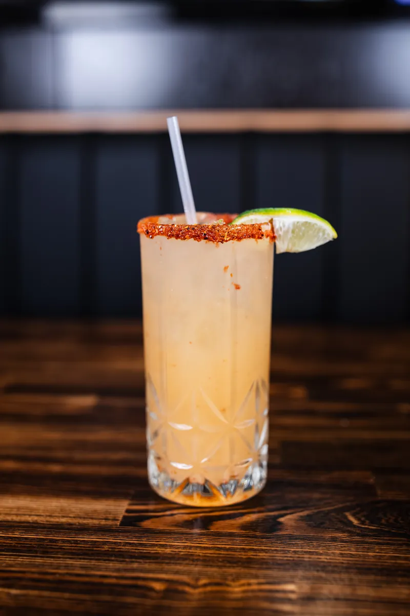 A tall drink with a chili-salt rim and a lime wedge