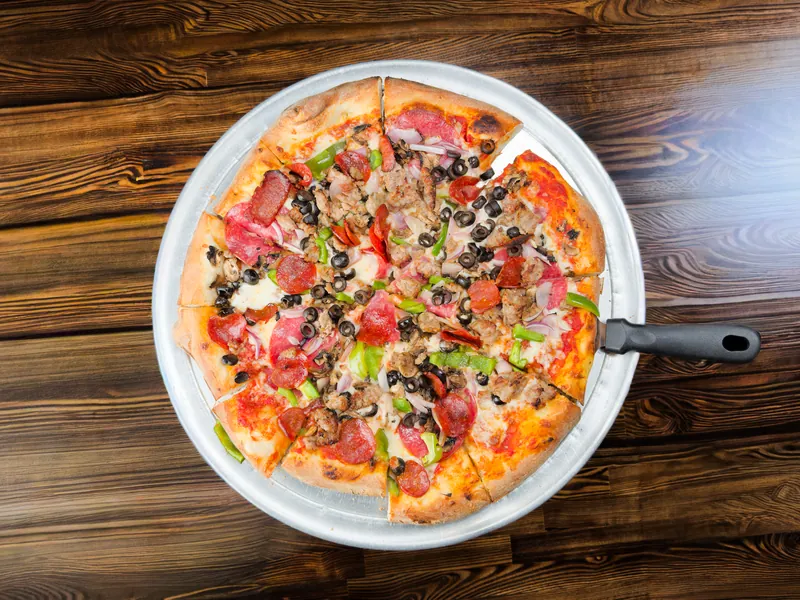 A pizza with pepperoni, sausage, olives, peppers, and onions, from above
