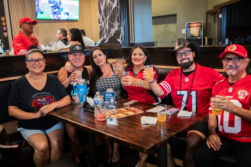 A table of guests in football jerseys raising their glasses