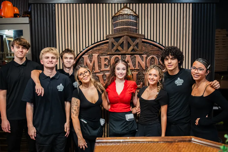 The Meganos Well team lined up in front of the sign