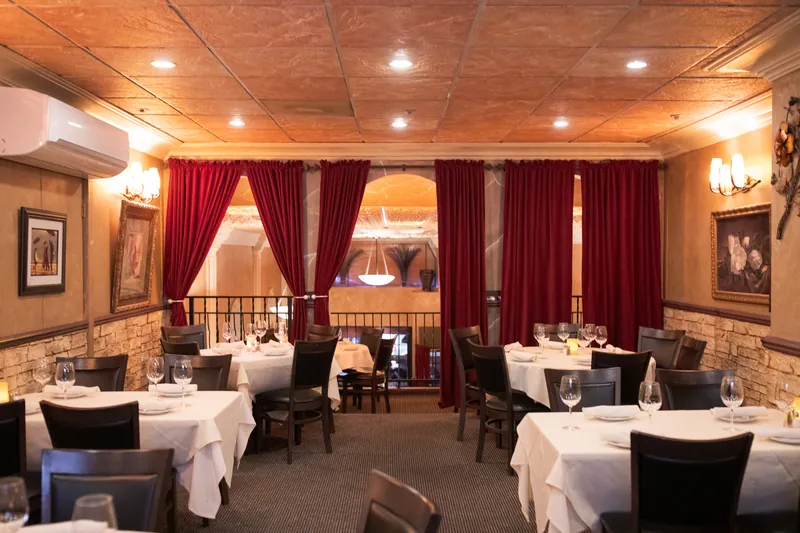 The dining room at Ristorante Rocca, red curtains and white tablecloths set for service