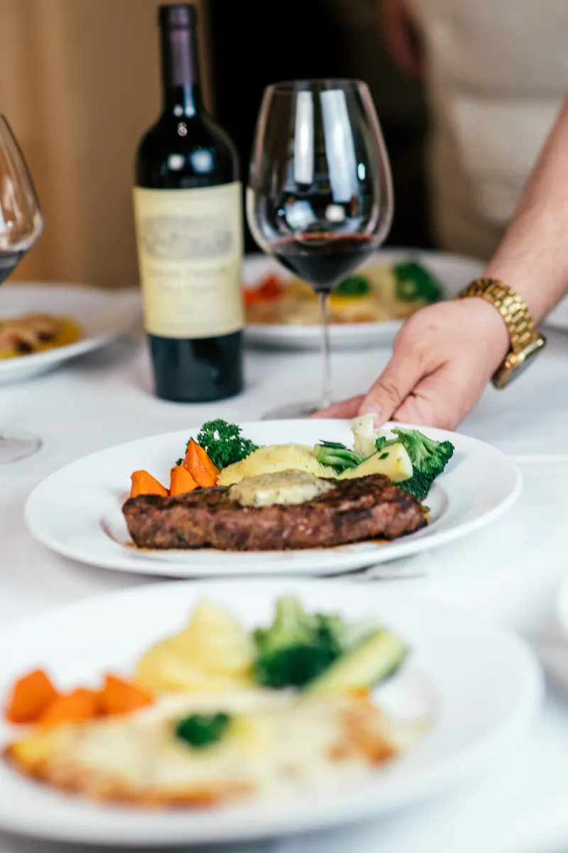 A server sets down a plated steak