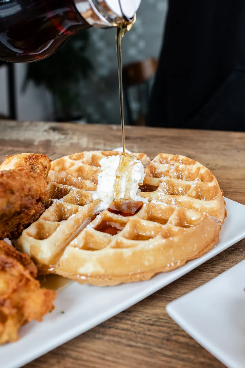 Syrup pouring over fried chicken and waffles
