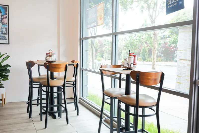 Window tables and wood-back stools in the bright dining room